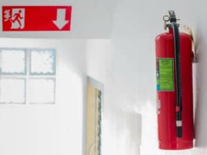 estintore sul muro e segnaletica di sicurezza per l'uscita di emergenza sullo sfondo